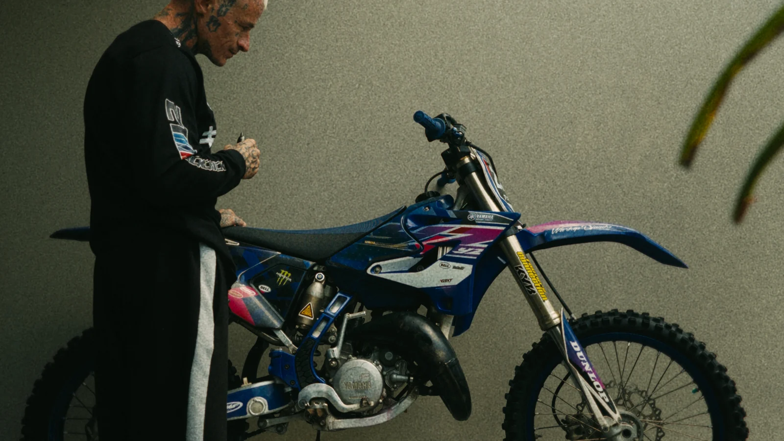 Charly auprès de sa moto de cross bleue